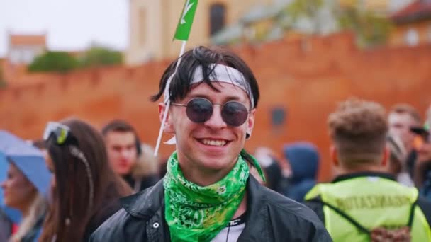 2022ポーランドのワルシャワ 20代か30代の若い白人男性がマリファナ マーチで サングラスをかけたカメラを見て ヘッドバンドに雑草の旗を掲げた 高品質4K映像 — ストック動画