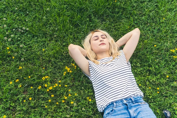 blond Caucasian girl dreaming on the grass and enjoying summer. medium shot. High quality photo