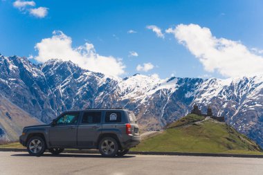 Gergeti Trinity Kilisesi 'nin arka planında bir araba ve inanılmaz Kafkasya dağları, Kazbegi, Georgia. Yüksek kalite fotoğraf