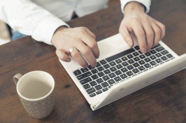 Kafkasyalı erkek çalışanın, atmosfer kahverengi masasında çalışan dizüstü bilgisayarın klavyesine yazı yazarken yakın çekimi. Yüksek kalite fotoğraf