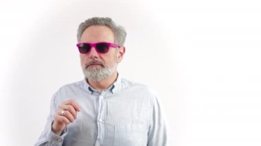 Orta yaşlı, gri saçlı bir adam sol arka plandaki stüdyoda fotokopi çekilirken güneş gözlüğünü çıkarırken kafasını çeviriyor. Yüksek kalite 4k görüntü