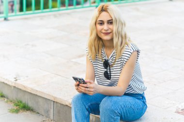 Avrupai genç bir kız oturuyor ve orta pişmiş kelle gibi gülümsüyor. Yüksek kalite fotoğraf