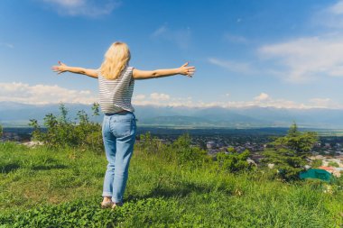 Alazani vadisi ve Gürcistan 'daki Kafkasya dağlarının muhteşem manzarası üzerinde uzanan sarışın kız. Tam doz. Yüksek kalite fotoğraf