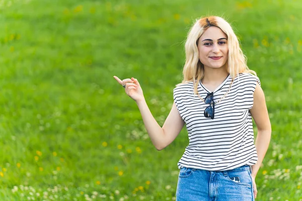 Young Caucasian Girl Pointing Smiling Grass Background Medium Shot Advertisement — Stock Photo, Image