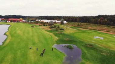 Zengin bir mahalle yakınlarındaki yeşil düz bir yüzey ve yoğun bir orman ile golf sahası ve bazı profesyonel oyuncular. Yüksek kalite 4k görüntü