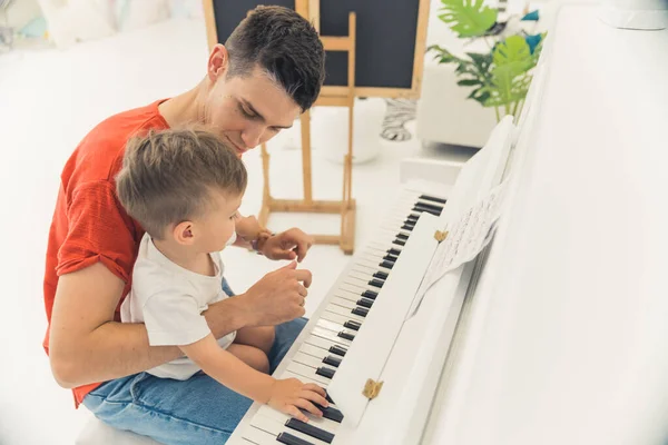 young father teaching his little son how to play the piano, medium shot. High quality photo
