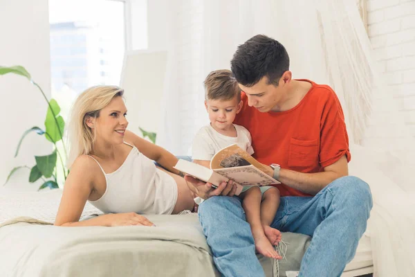 Caucasian parents reading a book for their little cute son, family concept. High quality photo