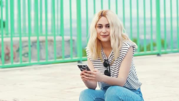 Medium Full Shot Young Blond Caucasian Girl Holding Her Phone — Stockvideo