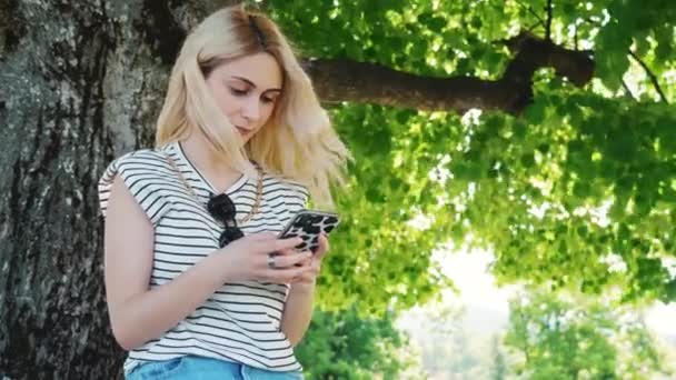 Rubia Chica Caucásica Sosteniendo Teléfono Mostrando Gesto Silencio Parque Medio — Vídeos de Stock