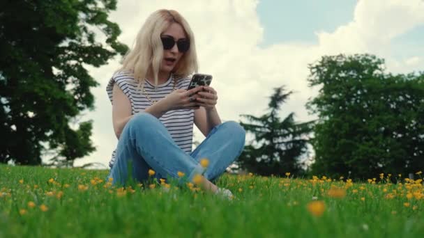 Blond Caucasian Girl Sitting Grass Using Her Mobile Phone Full — Wideo stockowe