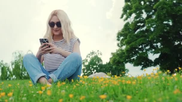 Full Shot Blond European Girl Grass Scrolling Social Media High — Vídeo de Stock