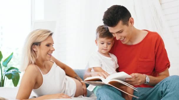 Família Feliz Mãe Grávida Pai Filho Pequeno Lendo Livro Casa — Vídeo de Stock