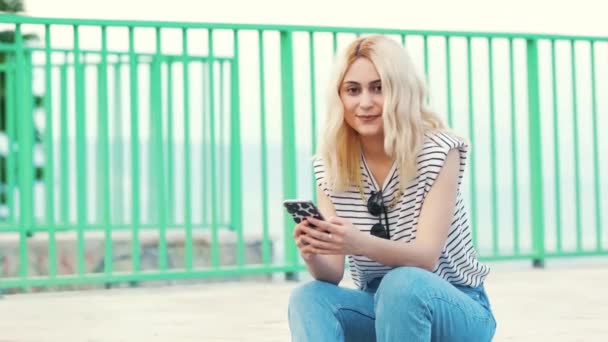 Bella Ragazza Caucasica Bionda Seduta Fuori Sorridente Nella Fotocamera Media — Video Stock