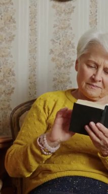 senior Caucasian woman holding the Bible and pondering medium shot living room religion and seniority concept. High quality 4k footage Vertical shot 