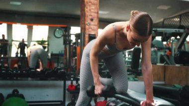 Vücut geliştirme egzersizleri konsepti. Gri renkli, şık spor elbiseli beyaz bir kız trisepsler için egzersiz yapıyor. - Evet. Yüksek kalite 4k görüntü