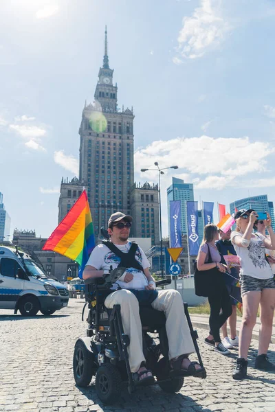 06.25.2022 Varşova, Polonya. Kültür ve Bilim Sarayı 'nın önünde tekerlekli sandalye kullanan engelli birinin dikey açılışı. LGBTQAI üyesi ya da gökkuşağı bayrağıyla müttefik. Yüksek