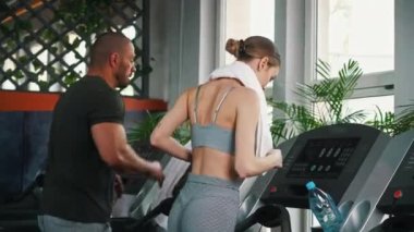 Beden eğitimi zamanı. En sevdikleri spor salonunda profesyonel koşu bandı kullanan iki kişi. Kardiyo egzersizleri. Yüksek kalite 4k görüntü