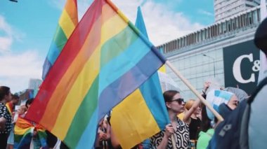 06.25.2022 Warsaw, Poland. Caucasian Equality Parade participants holding rainbow flags, transsexual flags, Polish flags, and Ukrainian flags. Equality and support for all concept. High quality 4k
