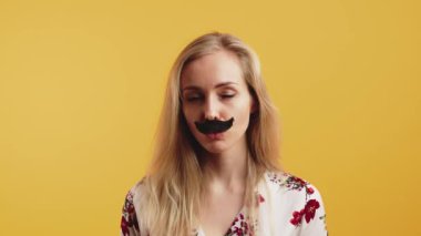 Hareket Konsepti. Kopya alanı, stüdyo çekimi, turuncu arka planda izole edilmiş. Beyaz çiçekli bluz giyen, beyaz saçlı, beyaz saçlı, beyaz saçlı, komik, beyaz saçlı, siyah bıyıklı bir kız.