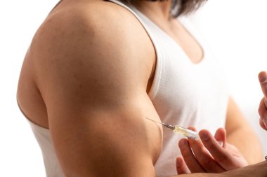 Beyaz kolsuz tişörtlü kaslı beyaz bir adam pazılarına bilinen bir madde enjekte ediyor. Esneme. Spor salonu. Stüdyo beyaz arka plan çekti. Doping konsepti. Yüksek kalite fotoğraf