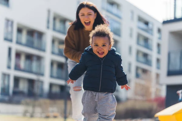 Young Grinning Caucasian Mother Chasing Her Interracial Toddler Motherhood Parenting — Stock fotografie