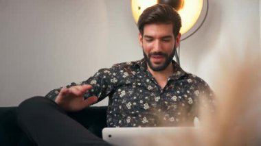 30 'larında mutlu ve yakışıklı bir Latin adam defteriyle konuşuyor ve ev ofis konseptini işaret ediyor. Yüksek kalite 4k görüntü