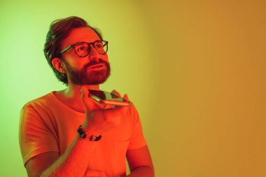 Kızıl saçlı adam iletişim kurmak için hoparlördeki akıllı telefonu kullanıyor. Yüksek kalite fotoğraf