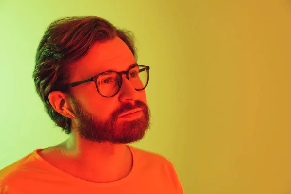 Portrait of an young hipster looking off the camera and thinking. Neon Lights. High quality photo