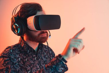 Portrait of a man with a vr headset and headphones touching the invisible touchscreen panel - virtual reality experience. High quality photo