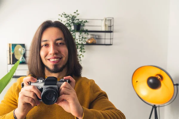 Sakallı, mutlu, gülümseyen bir adam elinde siyah bir kamera tutuyor. Yüksek kalite fotoğraf