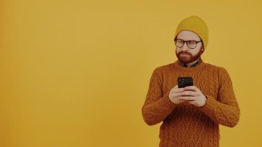 Sosyal medya bağımlısı akıllı telefonundaki uyarıları kontrol ediyor - haber ve sosyal medya kavramı - turuncu arka plan. Yüksek kalite 4k görüntü