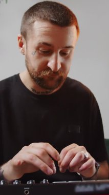 dikey video genç sakallı müzisyen MIDI klavye üzerinde müzik yaratıyor ve amstaff köpeği tam kare arka planda oturuyor. Yüksek kalite 4k görüntü