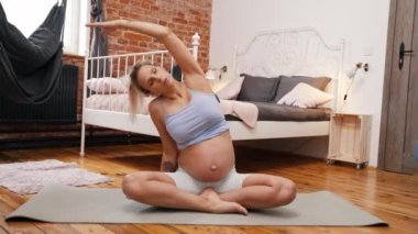 Genç, hamile, beyaz bir kadın. Rahatlıyor ve egzersiz yapıyor. Yüksek kalite 4k görüntü