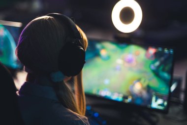 Kulaklık takan tanınmayan genç bir kız geniş ekranda halka ışığıyla oyun oynuyor. Oyun bilgisayarı kurulumu. - Evet. Yüksek kalite fotoğraf