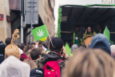 Kenevir gösterisi sırasında insanların kafalarının arkası. Üzerinde beyaz kenevir yaprağı resmi olan küçük yeşil bir bayrak. Demokrasi. Yüksek kalite fotoğraf