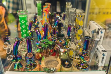 05.28.2022 Varşova, Polonya. Tıbbi marihuana ile ilgili ürünler. Sağlık sigortası konsepti. Cam bir ekranda duran çeşitli boyutlarda renkli bonglar. Yüksek kalite fotoğraf