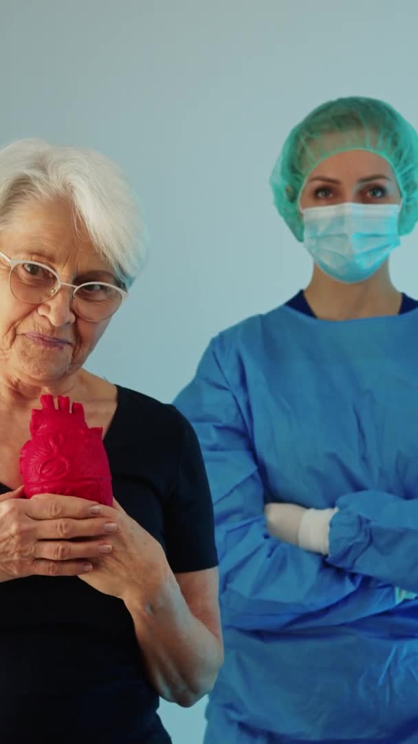 Old Caucasian Woman Standing Front Surgeon Doctor While Holding Red — Vídeos de Stock