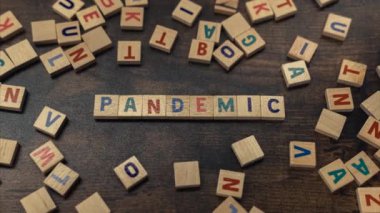 Symbolic depiction of the PANDEMIC with the use of colourful wooden letter puzzles creating that word. Post-covid world concept. Economy. High quality 4k footage