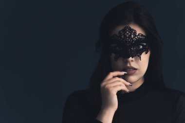 Siyah dantel bir maske takan esrarengiz beyaz kadın kameraya bakıyor. Karanlık arka plan stüdyo çekimi. Yüksek kalite fotoğraf