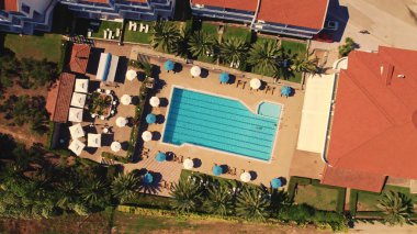 Yakınlarda beyaz ve mavi şemsiyeli küçük bir otel havuzu manzarası. Dünyanın dört bir yanından gelen turistler ve gezginler için hazır bir yer. Yüksek kalite fotoğraf