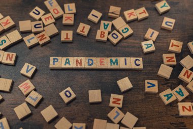 Symbolic depiction of the PANDEMIC with the use of colourful wooden letter puzzles creating that word. Post-covid world concept. Economy. High quality photo