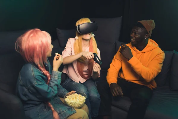 Two Teenage Friends Eating Popcorn Watching Girl Playing Virtual Reality — Stockfoto