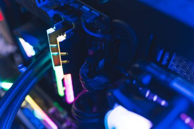Professional gaming computer setup close-up. Glowing parts in rainbow colors and cables. Dark blue lighting. High quality photo