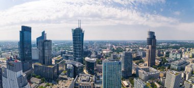 7.22.2022 Warsaw, Poland. Wide panoramic drone shot of Warsaw skyline. Such skyscrapers as Warsaw Trade Tower, Warsaw Spire, Skyliner, and Warsaw Unit seen from birds eye perspective. Beautiful sunny