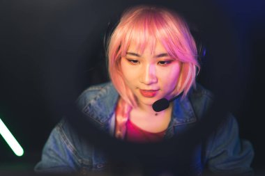 Pembe örgülü saçlı, kulaklık takan Asyalı genç bir kız rekabetçi bir oyun oynamaya odaklanmış. Yüksek kalite fotoğraf