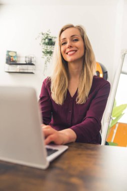 Laptop kullanan beyaz bir kız ve kameraya zevkle bakıyor. Arka plan yakın plan. Yüksek kalite fotoğraf