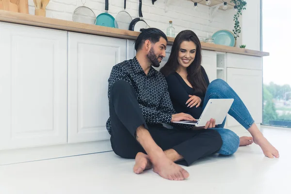 Young Couple Relaxing Barefoot Floor Kitchen Counter Using Laptop Smiling — стоковое фото