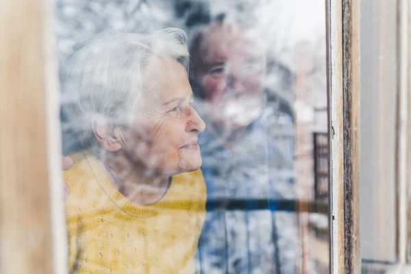 Caucasian Senior Married Couple Home Looking Frosty Window Admiring Snow — Stock Photo, Image