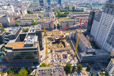 Eclectic architecture concept. Construction of a skyscraper or block of flats. Three professional cranes and construction workers doing their job. Aerial view. . High quality photo