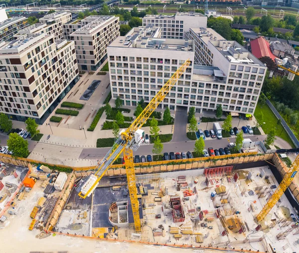 Square aerial drone perspective of construction site in the centre of Warsaw. Two yellow cranes working on a new building. High quality photo